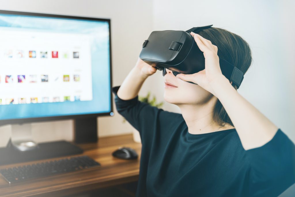 woman looking into a virtual reality headset at a desk